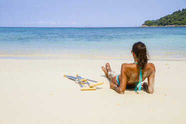 Thailand, Koh Surin island, woman with crutches lying at the white sandy beach - MBEF000724
