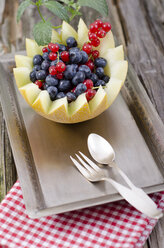 Honigmelone mit roten Johannisbeeren und Blaubeeren, Tablett auf Holztisch, Nahaufnahme - OD000345