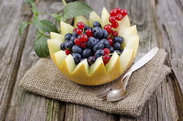 Honigmelone mit Heidelbeeren und roten Johannisbeeren auf Holztisch, Nahaufnahme - OD000346