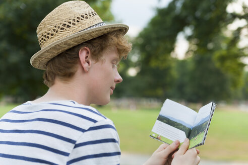 Junger Mann mit Hut beim Lesen im Freien - TCF003566