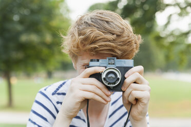 Young man taking a picture in park with an old-fashioned camera - TCF003570
