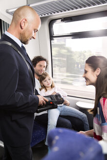 Deutschland, Brandenburg, Schaffner bei der Fahrkartenkontrolle einer Familie - KFF000212