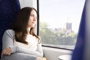 Germany, Brandenburg, Mid adult woman looking through window in train - KFF000219