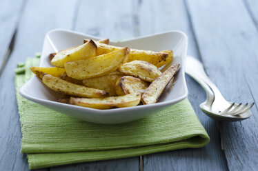 Schüssel mit Bratkartoffeln mit Serviette auf Holztisch, Nahaufnahme - OD000379