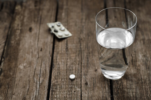 Pill and glass of water on wooden table, close up - CZF000065