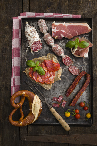 Aufschnittplatte mit Cocktailtomaten, Brezel, frischem Basilikum, Chorizo, Salami, Prosciutto, lizenzfreies Stockfoto