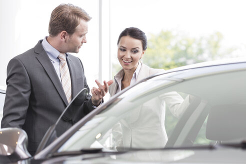 Beim Autohändler, Verkäufer zeigt dem Kunden ein neues Auto - MLF000017