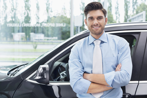 Beim Autohändler, Porträt eines selbstbewussten Verkäufers, lizenzfreies Stockfoto