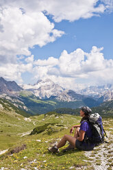 Italy, South Tyrol, Dolomites, Fanes-Sennes-Prags Nature Park, hiker sitting in alpine meadow - UM000644