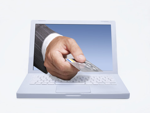 Manager gibt eine Kreditkarte durch einen Laptop-Bildschirm, digitales Komposit, lizenzfreies Stockfoto