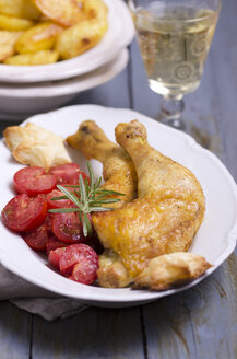 Maishähnchen mit gebratenen Tomaten, Kartoffelspalten und einem Glas Weißwein - ODF000395