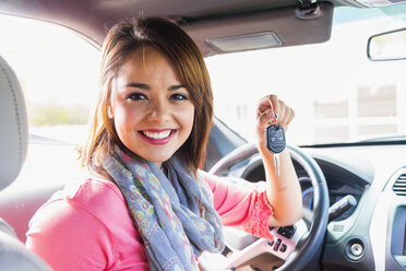 Smiling teenage girl inside car holding key - ABAF000995