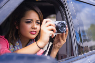 Teenage girl taking picture out of car - ABAF000997