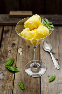 Mango pineapple sorbet in a glass on a wooden table with fresh basil, close-up - CZF000079