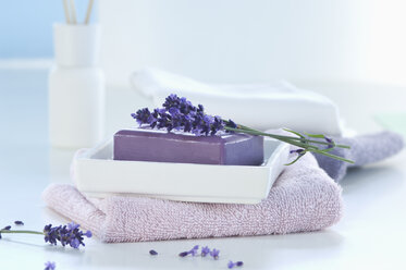 Lavendelzweige auf einem Stück Lavendelseife, Seifenschale und einem Handtuch - ASF005151