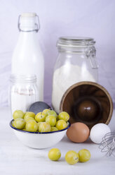 Cake pan, flour, eggs, milk, sugar, mirabelles and egg whip on table - ODF000431