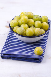 Mirabelles in a bowl and a dish towel on wooden table - ODF000433