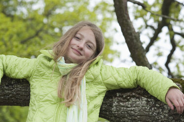 Deutschland, Bayern, Mädchen lehnt an einem Baumast - CRF002484