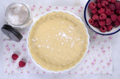 Roher Mürbeteig in Auflaufform mit Himbeeren und Zucker, lizenzfreies Stockfoto