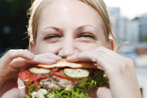Junge Frau beim Essen eines Hamburgers, lizenzfreies Stockfoto