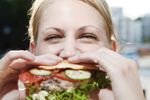 Junge Frau beim Essen eines Hamburgers - FEXF000039