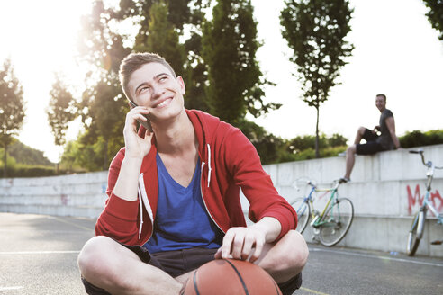 Junger Mann mit Smartphone und Basketball - FEXF000032