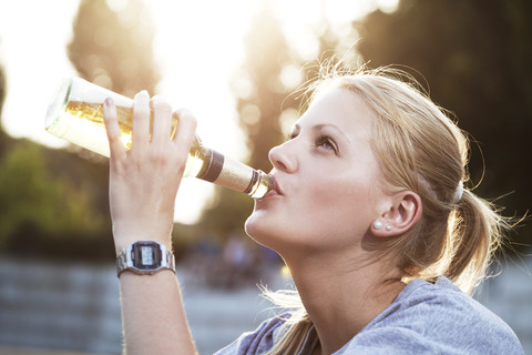 Young woman drinking beer of a bottle stock photo