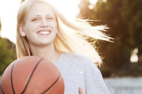 Lächelnde junge Frau mit Basketball - FEXF000049