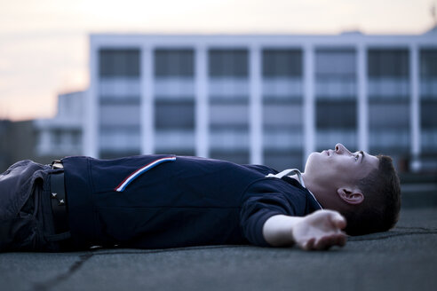 Junger Mann auf Flachdach liegend - FEXF000017