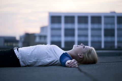 Young woman lying on flat roof stock photo