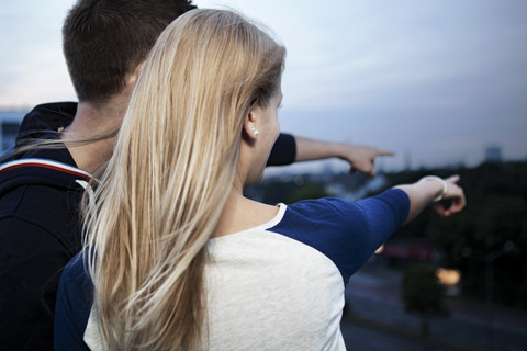 Junges Paar auf Flachdach in der Morgendämmerung, lizenzfreies Stockfoto