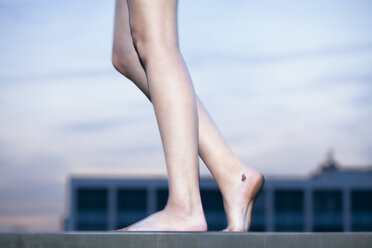 Nackte Beine einer jungen Frau mit kleinem Tatoo auf ihrem rechten Fuß - FEXF000008