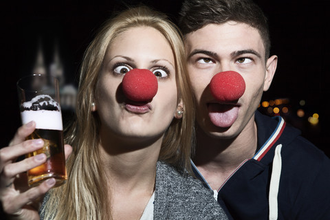 Germany, North Rhine Westphalia, Cologne, young couple with clowns noses toasting stock photo