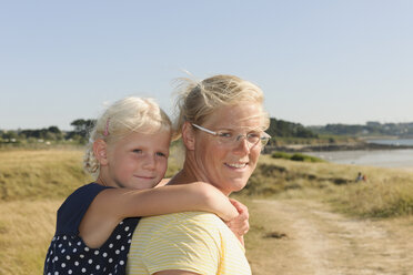 France, Bretagne, Landeda, Mother carrying daughter piggyback - LAF000129