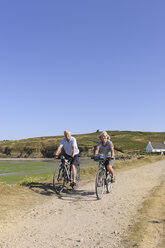 Frankreich, Bretagne, Finistere, Seniorenpaar auf E-Bikes an der Küste - LA000149