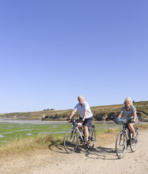 Frankreich, Bretagne, Finistere, Seniorenpaar auf E-Bikes an der Küste - LA000150