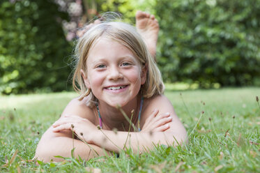 Lächelndes Mädchen im Gras liegend - NHF001420