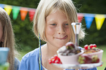 Girl looking at muffins on a birthday party - NHF001469