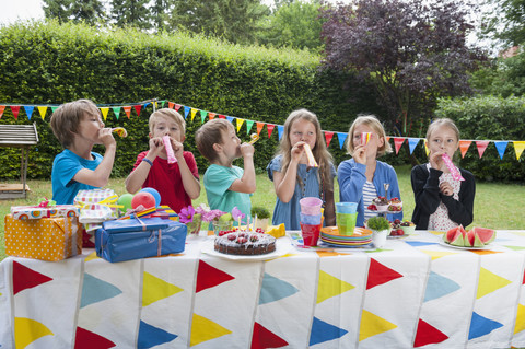 Kinder benutzen Partybläser auf einer Geburtstagsfeier, lizenzfreies Stockfoto