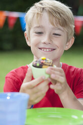 Happy boy eating muffin on a birthday party - NHF001446