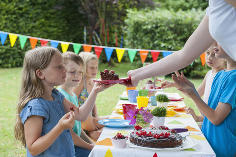 Mädchen erhält ein Stück Kuchen auf einer Geburtstagsparty, lizenzfreies Stockfoto