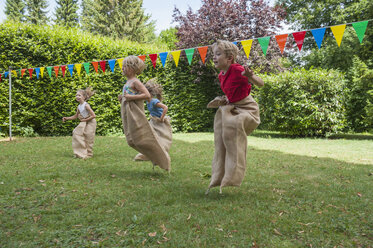 Children having a sack race in garden on a birthday party - NHF001462