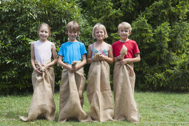 Four children standing in sacks side by side - NHF001460