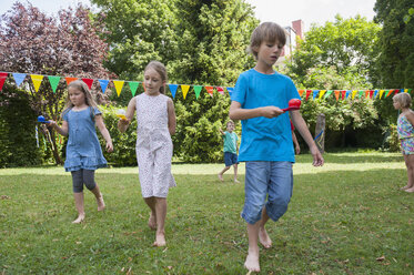 Children having a spoon and egg race in garden on a birthday party - NHF001458