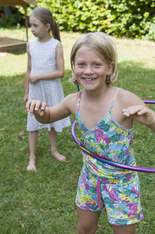 Happy girl with hula hoop in garden stock photo