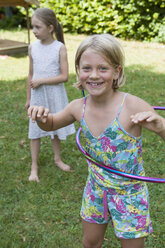 Happy girl with hula hoop in garden - NHF001457