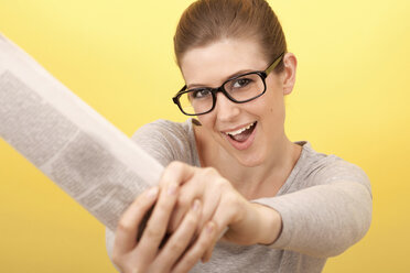 Junge Frau mit Brille hält eine Zeitung, Porträt - DRF000205
