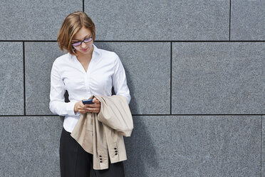 Germany, Businesswoman holding smart phone - RKNF000149