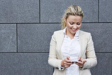 Germany, Businesswoman holding smart phone - RKNF000147