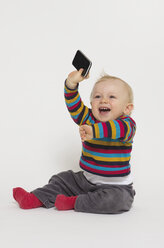 Baby boy playing with smart phone, studio shot - MUF001403